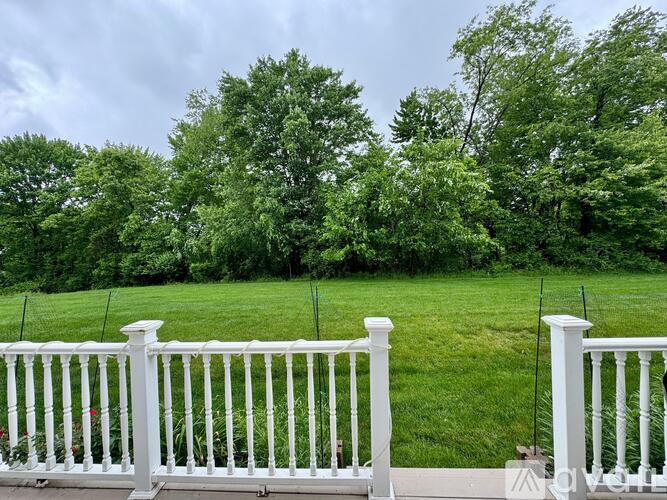A white fence in front of a green lawn and trees.