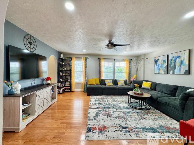A living room with a green couch and a rug on the floor.