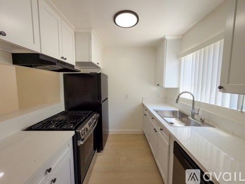 A kitchen with white cabinets and a black stove top oven.