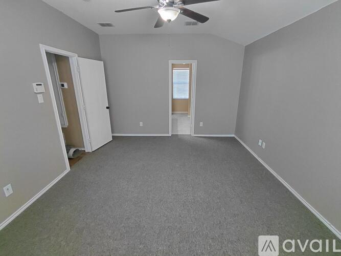 A spacious room with a ceiling fan and two doors.