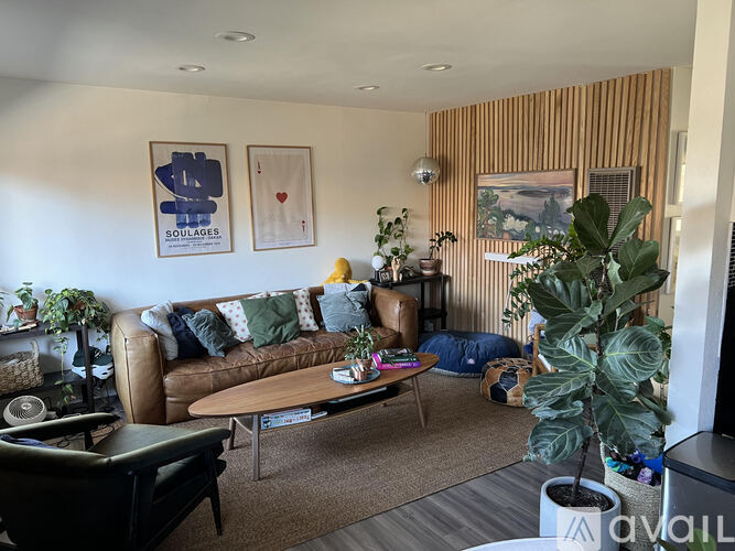 A living room with a couch, coffee table, and plants.