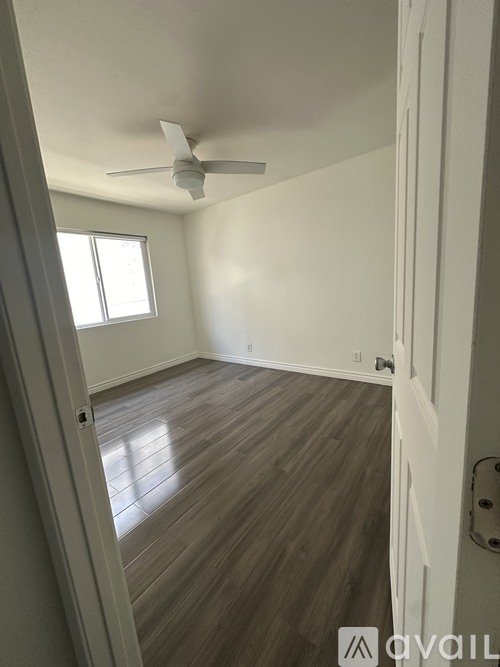 A room with a ceiling fan and wooden flooring.