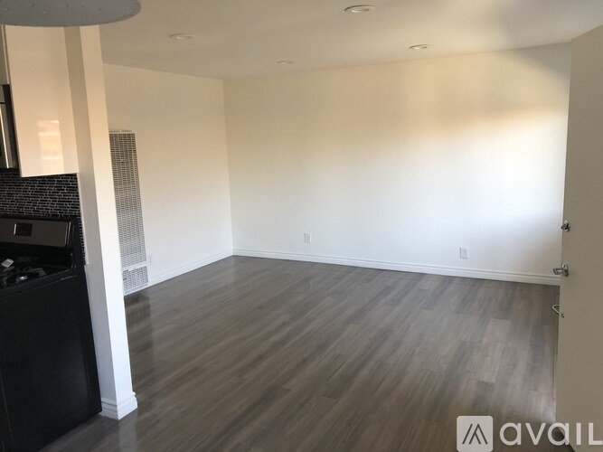 A spacious room with wooden flooring and white walls.