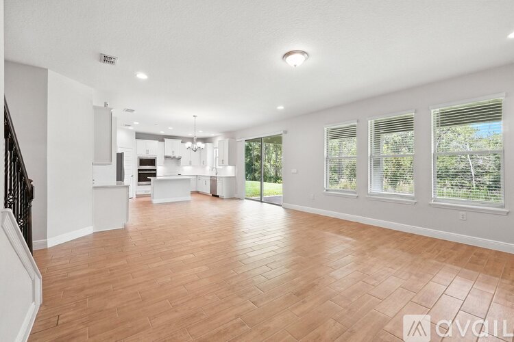A spacious living room with hardwood floors and a staircase on the left side.