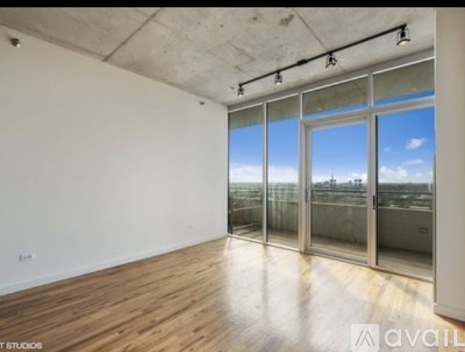 A spacious room with wooden floors and large windows overlooking a cityscape.