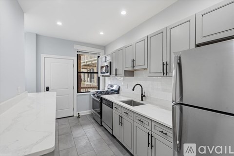 A modern kitchen with a marble countertop and stainless steel appliances.