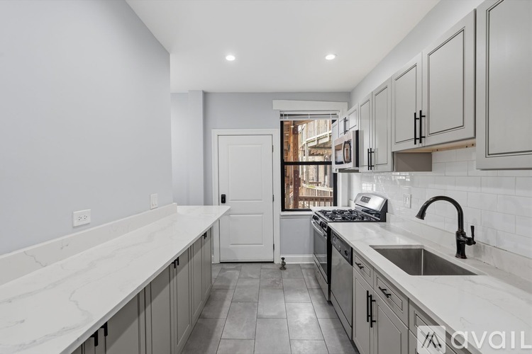 A kitchen with marble countertops and a stainless steel sink.