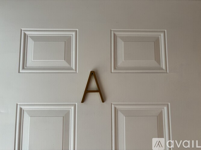 A wooden letter A is in the middle of four white frames on a white wall.