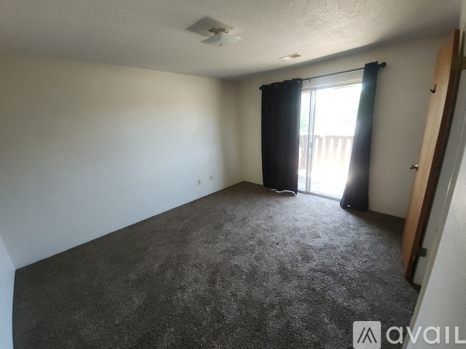 A room with a carpeted floor and a sliding glass door leading to a balcony.