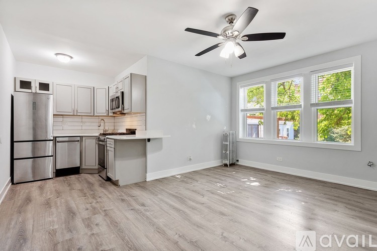 A spacious kitchen with a refrigerator, microwave, and a fan on the ceiling.