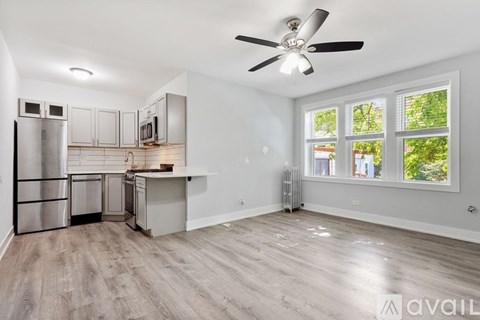 A spacious kitchen with a refrigerator, microwave, and a fan on the ceiling.