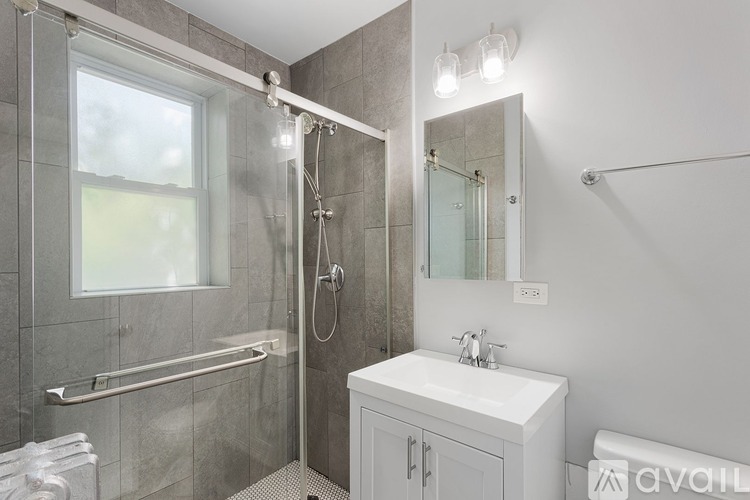 A bathroom with a white sink and a glass shower door.