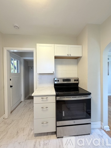 A kitchen with a stove top oven and white cabinets.