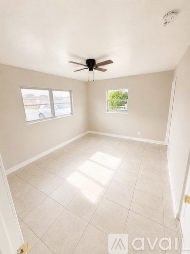 A room with a ceiling fan and two windows.