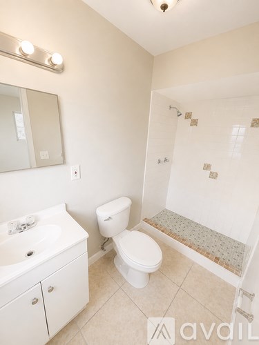 A white bathroom with a toilet, sink, and shower.