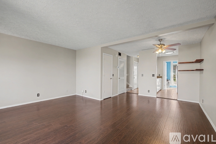 A spacious room with wooden floors and a ceiling fan.