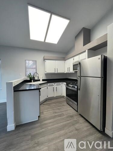 A modern kitchen with stainless steel appliances and a skylight.