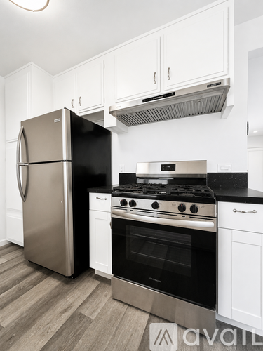 A kitchen with a stainless steel refrigerator and a black stove top oven.