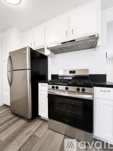 A kitchen with a stainless steel refrigerator and a black stove top oven.