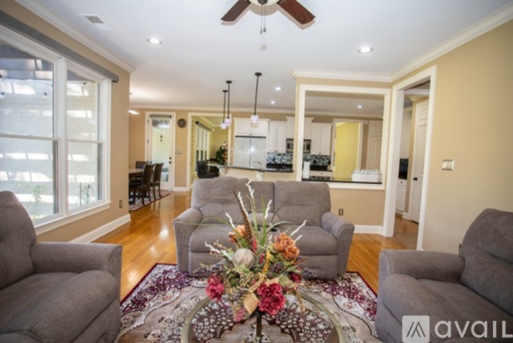 A living room with a rug, chairs, and a flower arrangement in the middle.