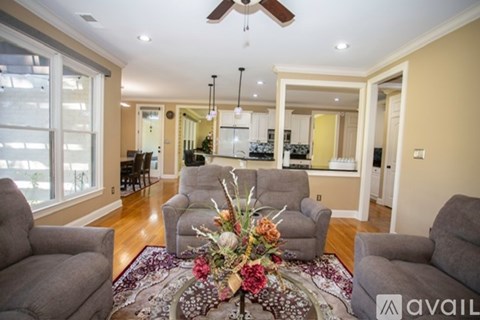 A living room with a rug, chairs, and a flower arrangement in the middle.