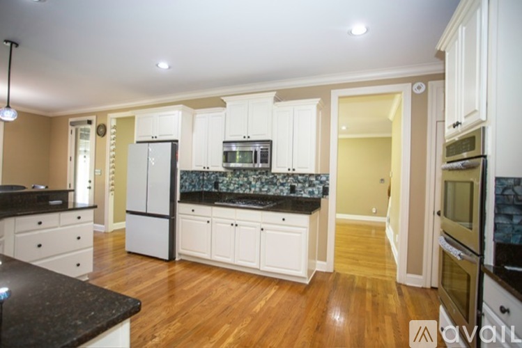 A kitchen with white cabinets and black countertops.