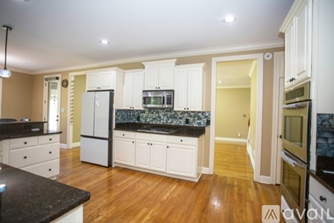 A kitchen with white cabinets and black countertops.