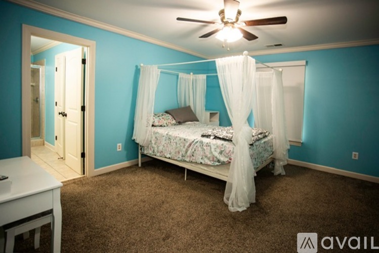 A bedroom with a canopy bed and a ceiling fan.