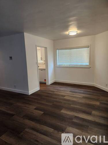 A room with wooden flooring and a window with blinds.