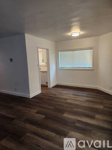 A room with wooden flooring and a window with blinds.