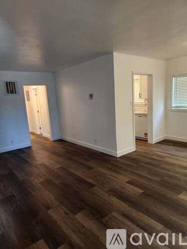 A room with wooden flooring and white walls.