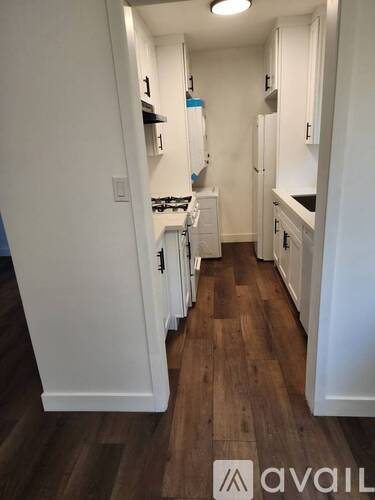 A kitchen with white cabinets and wooden floors.