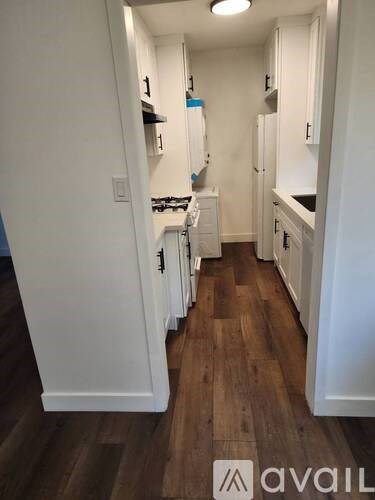 A kitchen with white cabinets and wooden floors.