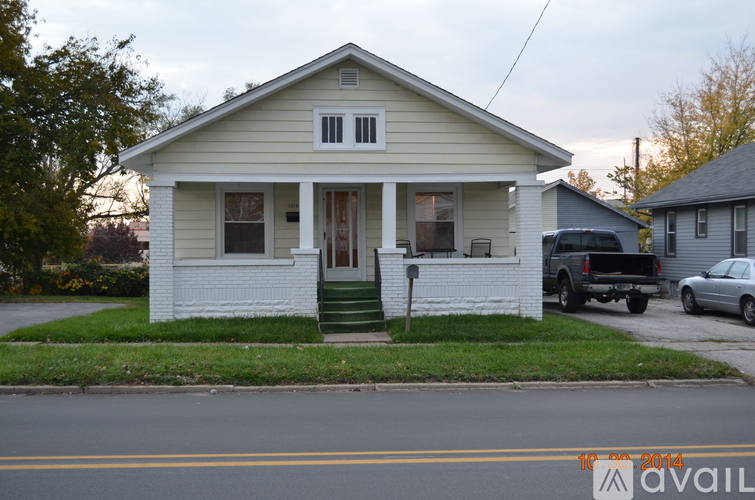A small white house with a porch and a truck parked in front.