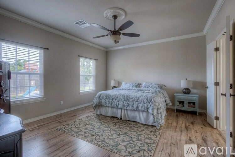 A bedroom with a bed, a ceiling fan, and a window with blinds.