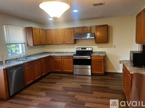 A kitchen with wooden cabinets and a black dishwasher.
