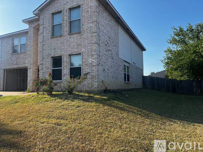 A house with a grey brick exterior and a green lawn in front.