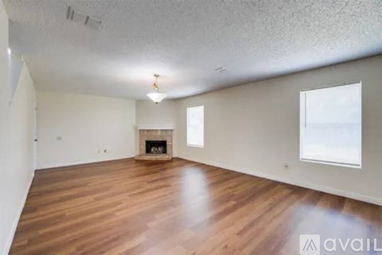 A spacious room with wooden flooring and a fireplace.