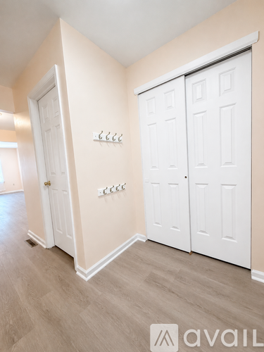 A room with a white door and a white wardrobe with a logo on the bottom right.