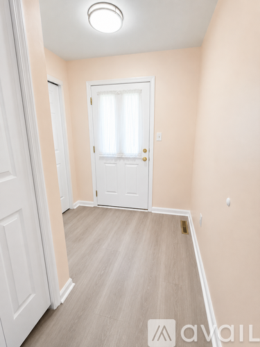 A room with a white door and a window with white curtains.