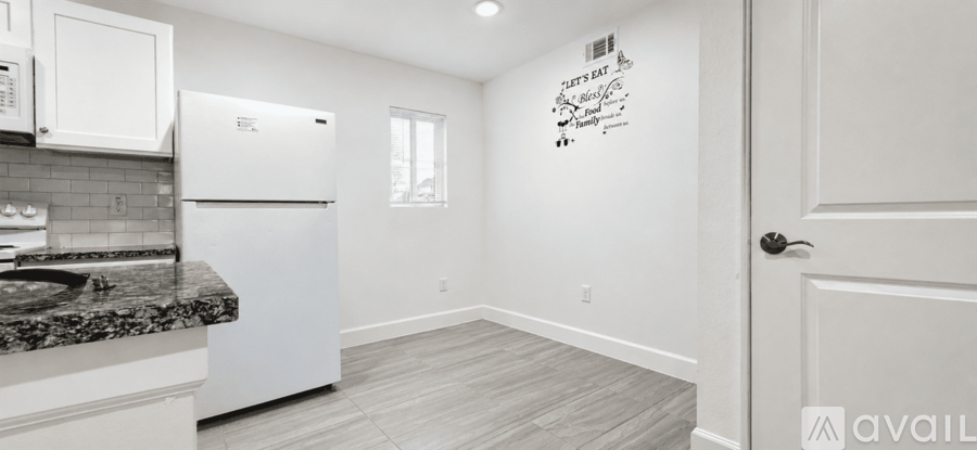 A kitchen with white appliances and cabinets, a granite countertop, and a wooden floor.