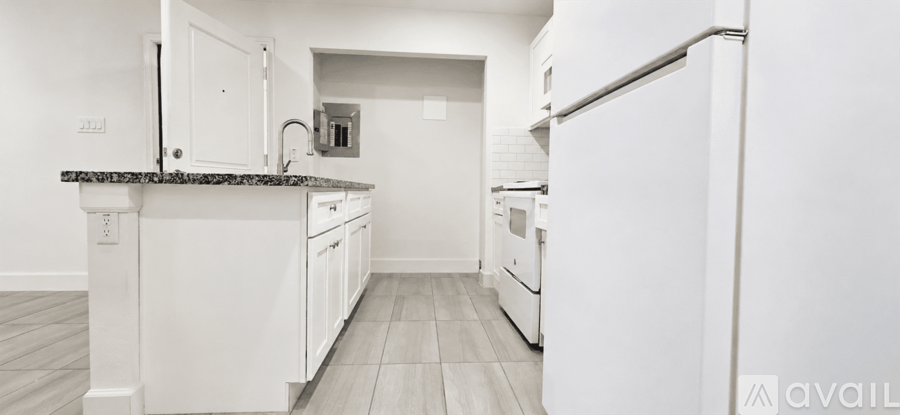 A kitchen with white cabinets and a black countertop.