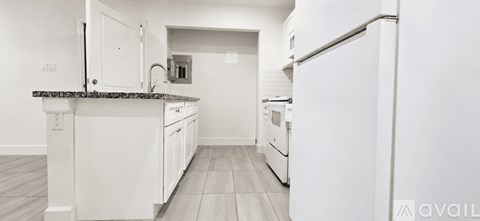 A kitchen with white cabinets and a black countertop.