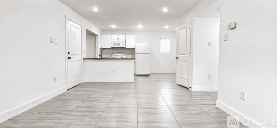 A spacious kitchen with white cabinets and a refrigerator.
