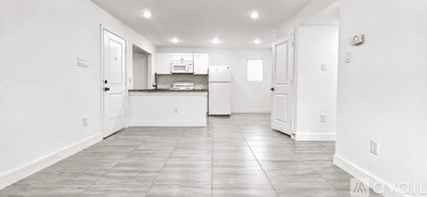 A spacious kitchen with white cabinets and a refrigerator.
