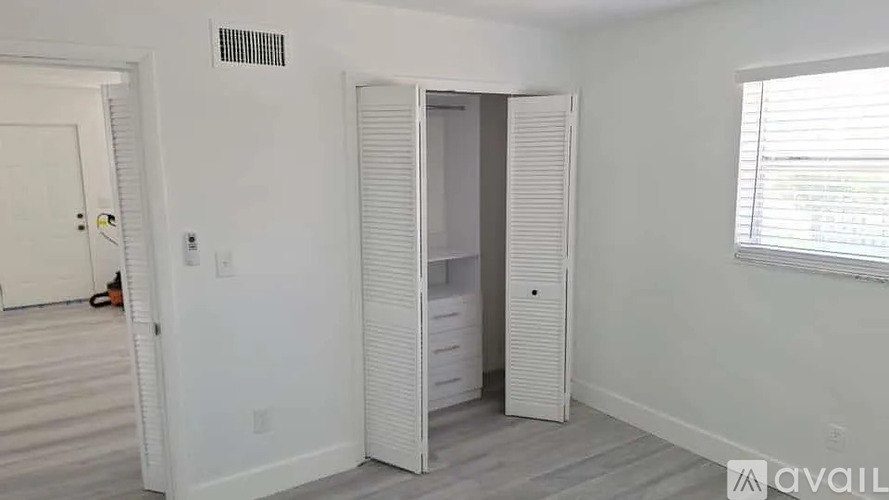 A room with a white door, a white cabinet, and a window with blinds.