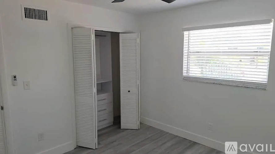 A room with a white door and a window with blinds.