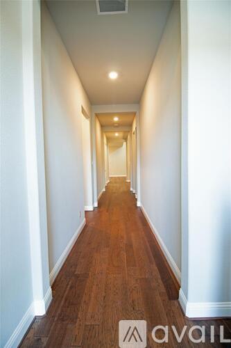 A long hallway with wood floors and white walls.