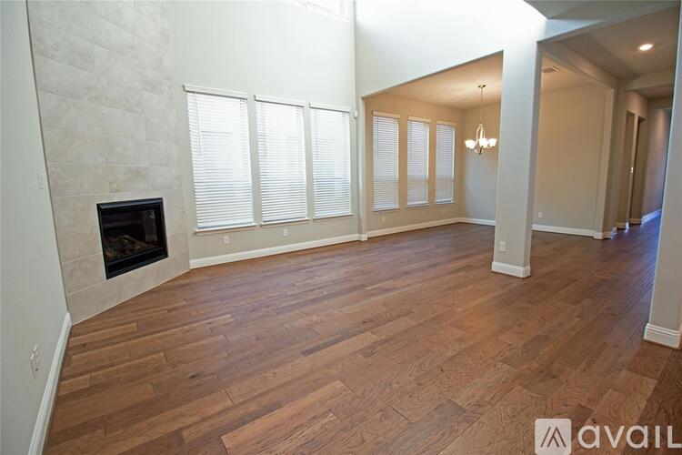 A spacious living room with wood flooring and a fireplace.
