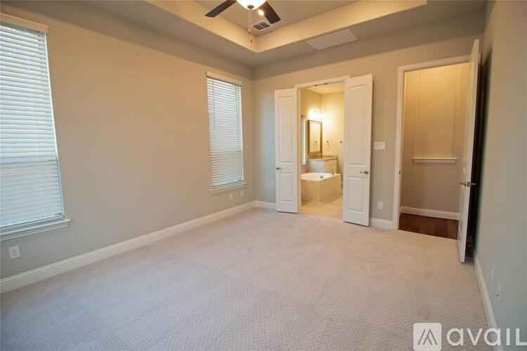 A spacious room with a carpeted floor and a ceiling fan.